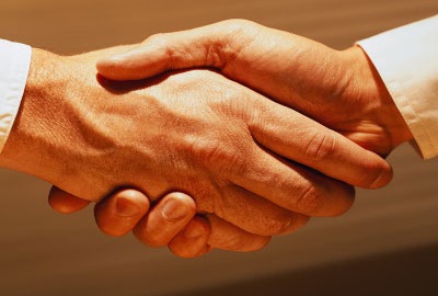 Image of two businessmen in shirt sleeves shaking hands depicting the need to apologize if you are in customer service.