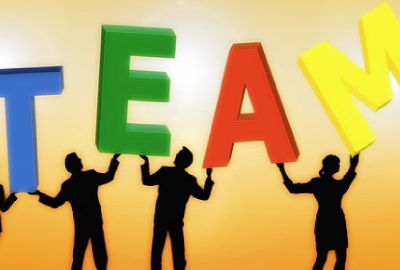 Image of four people holding up the letters 'TEAM', depicting the need to evaluate team performance.