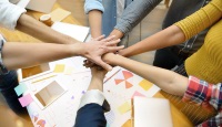 People placing hands in group circle depicting team organization.